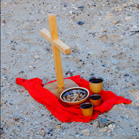 Holzkreuz und Abendmahl auf Sand