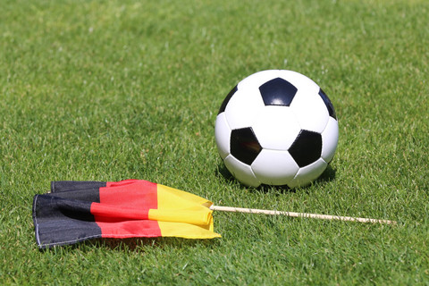 Ein Fußball und eine Deutschlandfahne liegen auf dem Rasen.