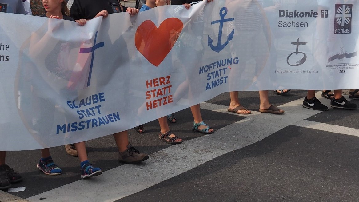 Banner Glaube statt Misstrauen - Herz statt Hetze - Hoffnung statt Angst mit Kreuz, Herz und Anker