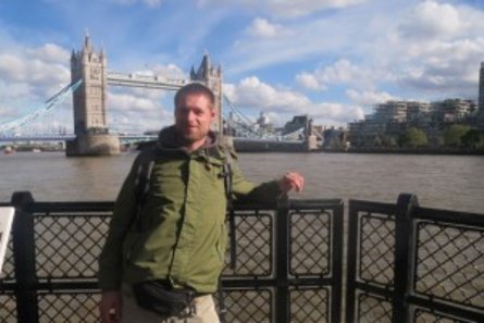 Ein junger Mann steht vor der Tower Bridge in London.