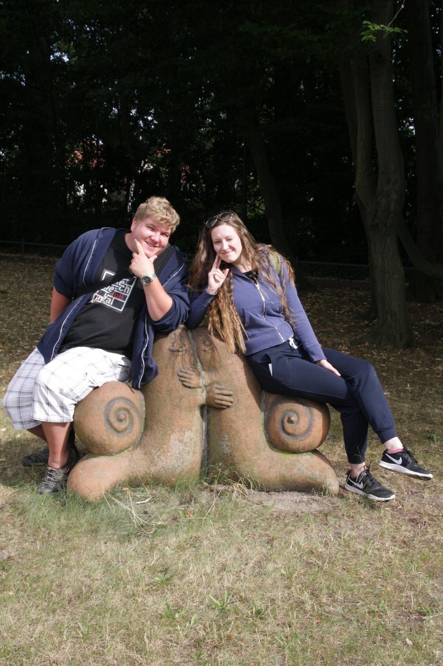 Johannes und Saskia lehnen bzw. sitzen auf einer Skulptur.