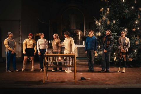 Hinter einer Futterkrippe stehen verschiedene Personen. Mehrere davon haben Kleidung an die zeigen soll, dass sie Bodybuilder sind. 