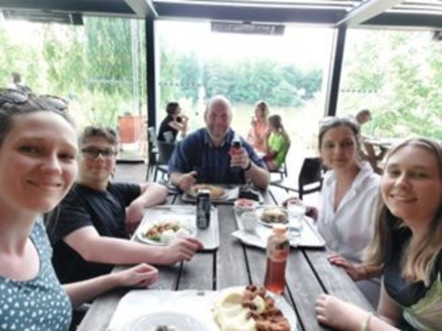 Viele verschiedene Menschen essen gemeinsam an einem Tisch.