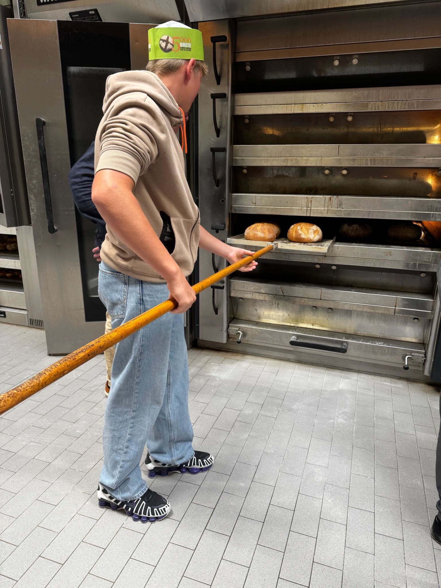 Brote werden mit einem langen Brotschieber aus dem Ofen geholt.