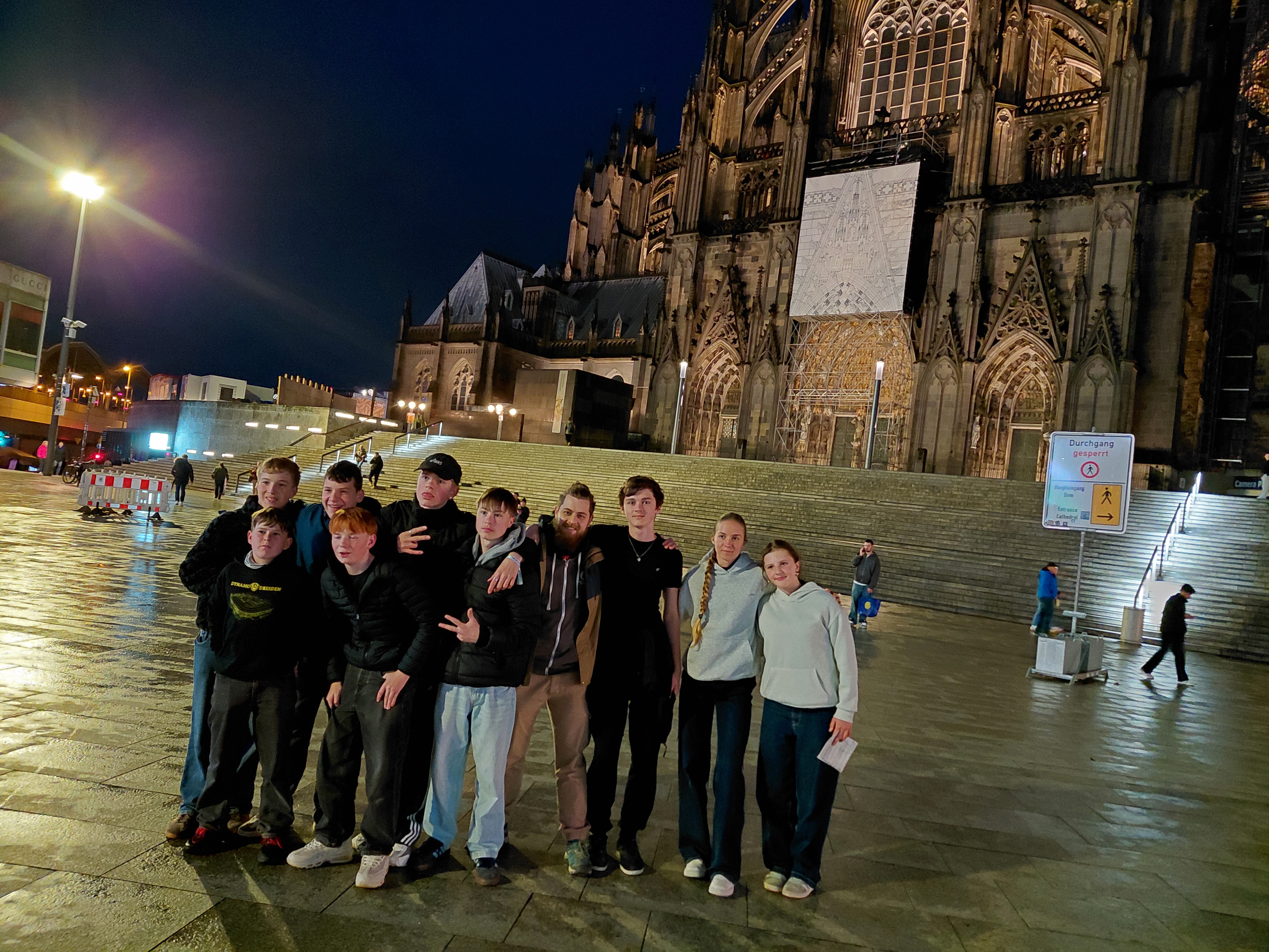 Zehn junge Menschen als Gruppe. Im Hintergrund ist der Kölner Dom zu sehen.