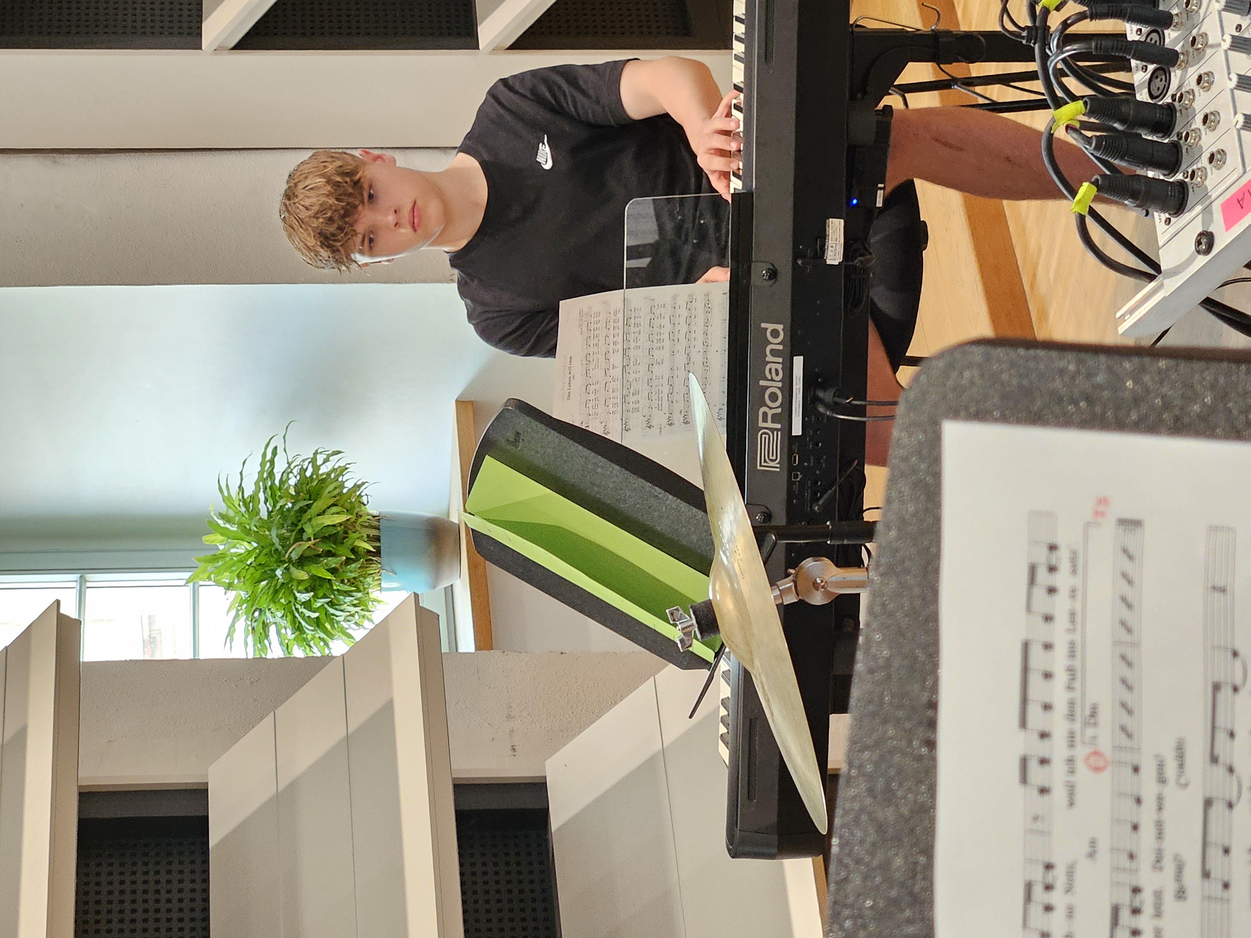 Ein männlich gelesener Jugendlicher sitzt am Klavier und spielt.