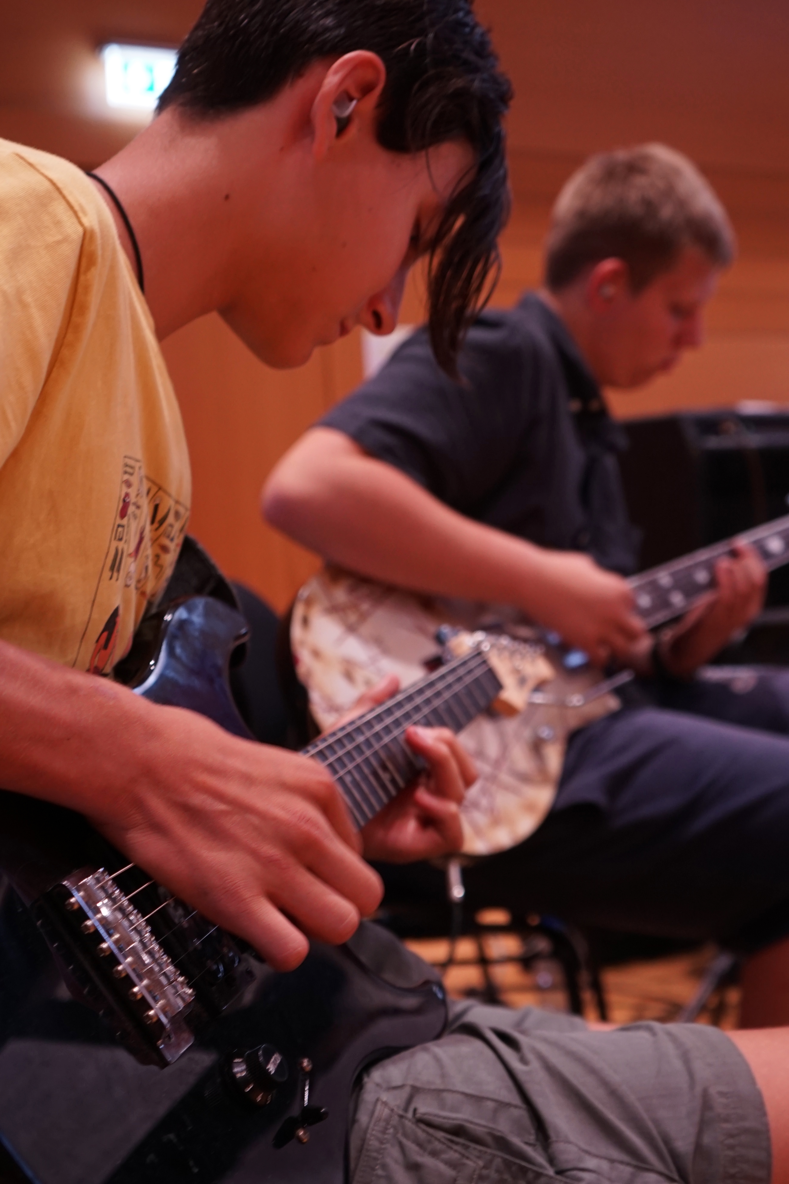 Zwei männliche Jugendliche mit E-Gitarren. Sie üben etwas.