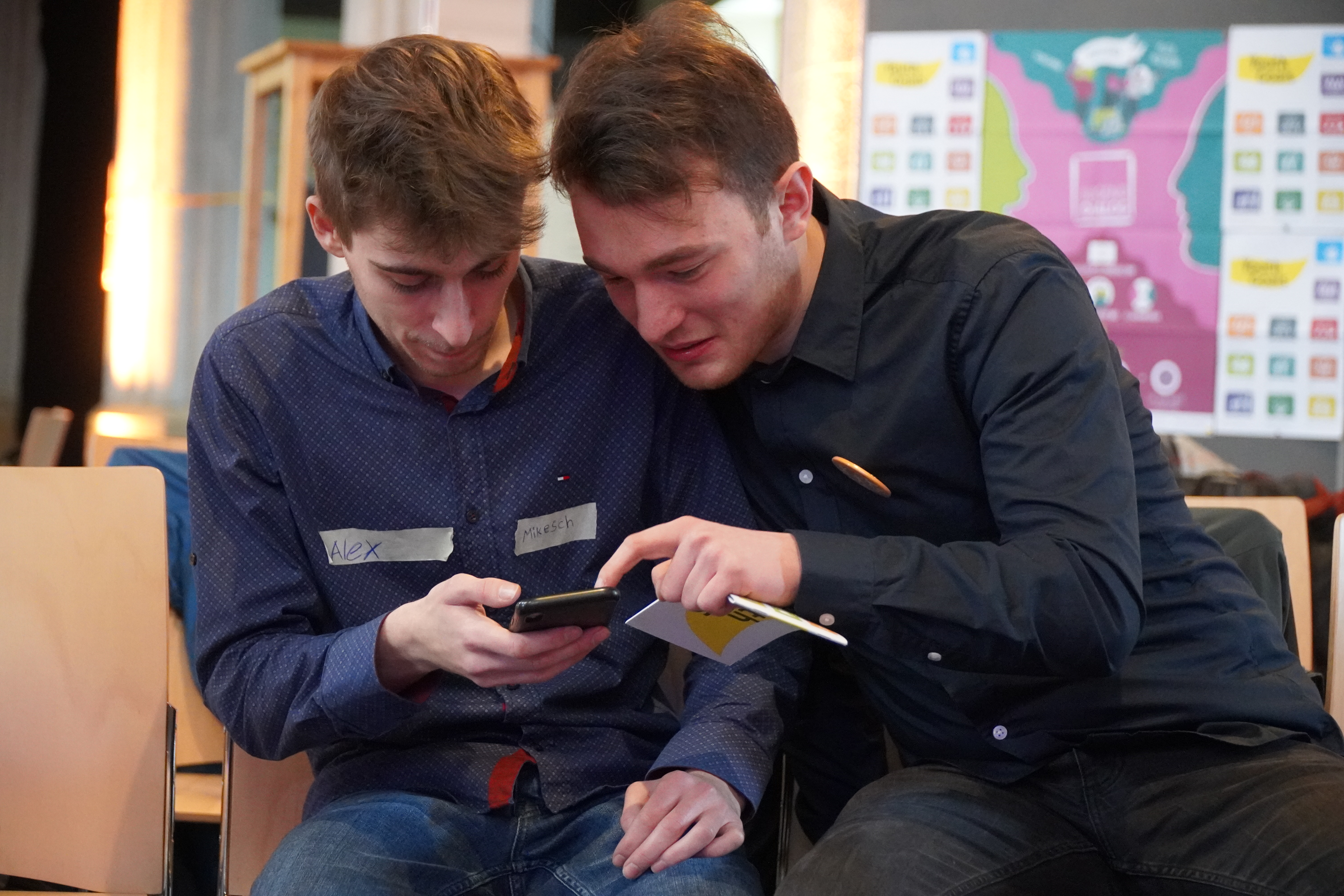 Zwei Teilnehmende schauen gemeinsam auf ein Handy.